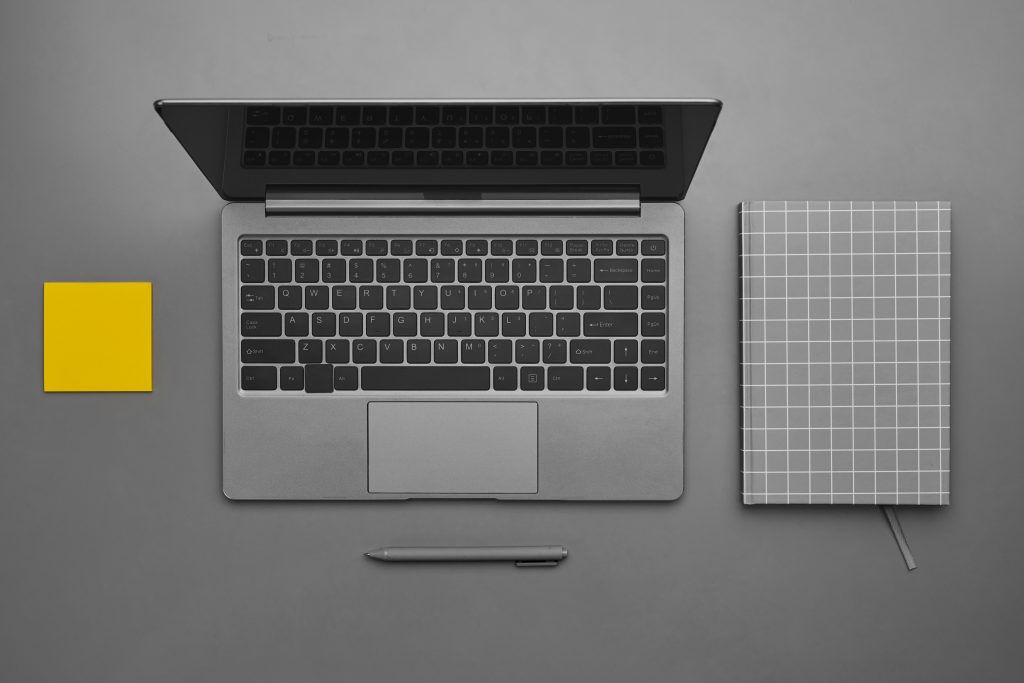 Graphic gray and yellow background of laptop with business accessories at desk, flatlay top down view, copy space
